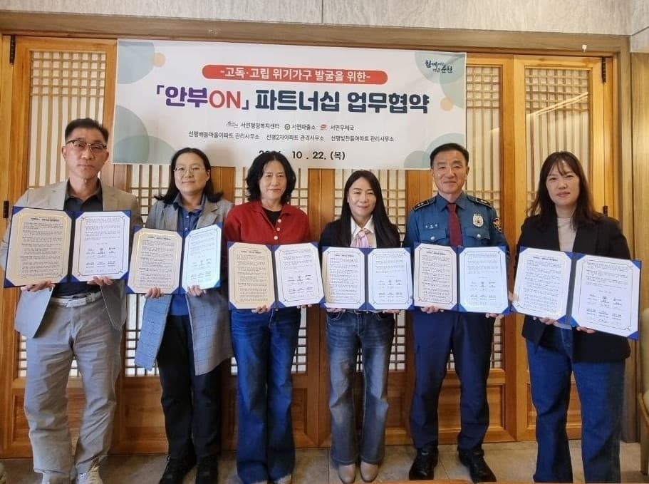 안부ON 협약 현수막 앞에서 협약서를 펼쳐 든 서면 유관기관 관계자들